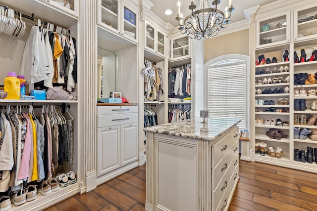 spacious closet with a chandelier and dark wood finished floors