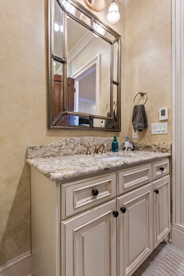 bathroom featuring vanity, ornamental molding, and a textured wall