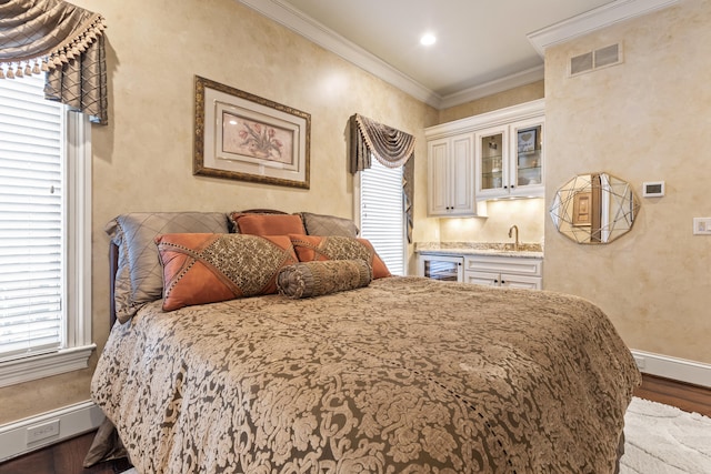 bedroom with wood finished floors, ornamental molding, baseboards, a sink, and beverage cooler
