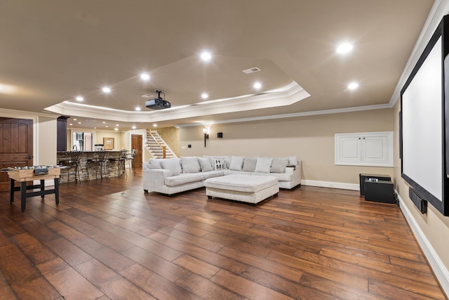 cinema featuring a tray ceiling, ornamental molding, dark wood-style floors, recessed lighting, and baseboards