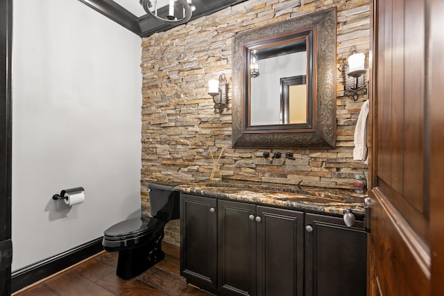 bathroom with toilet, vanity, crown molding, and wood finished floors