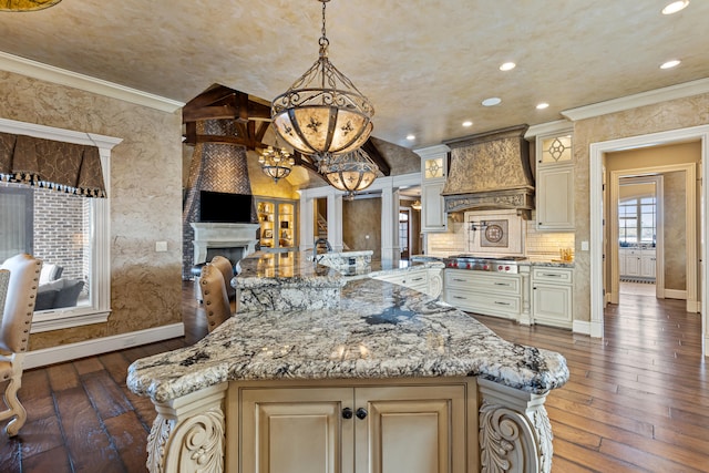 kitchen with custom exhaust hood, cream cabinetry, dark wood-style floors, open floor plan, and light stone countertops