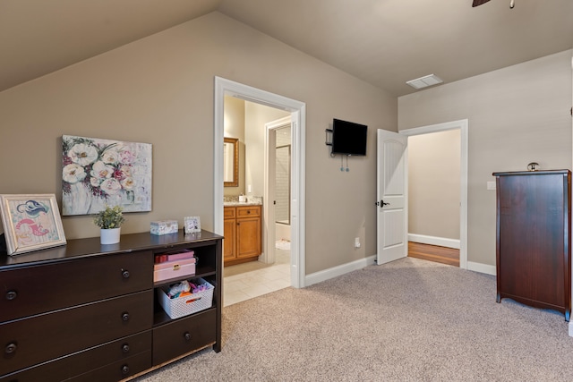 bedroom featuring light carpet, vaulted ceiling, ensuite bathroom, and baseboards