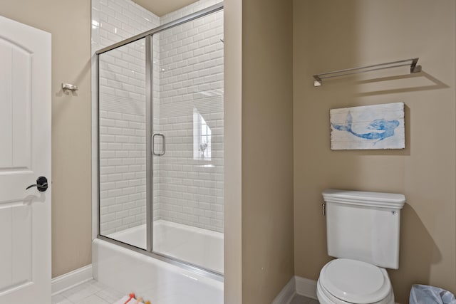 full bath featuring baseboards, bath / shower combo with glass door, tile patterned flooring, and toilet