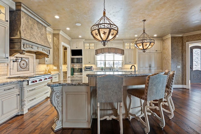 kitchen with plenty of natural light, a kitchen island with sink, a chandelier, a kitchen bar, and recessed lighting