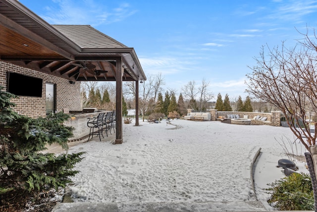 yard layered in snow featuring a fire pit, ceiling fan, and a patio area