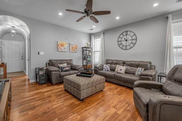 living area featuring light wood-style flooring, ceiling fan, recessed lighting, and arched walkways