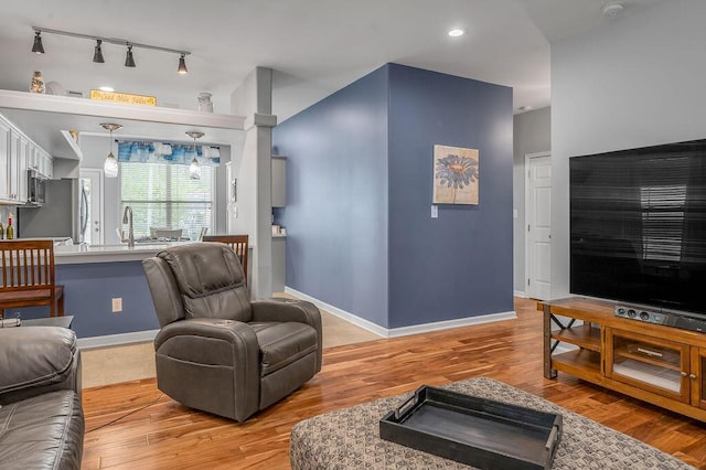 living area featuring rail lighting, light wood-style floors, and baseboards