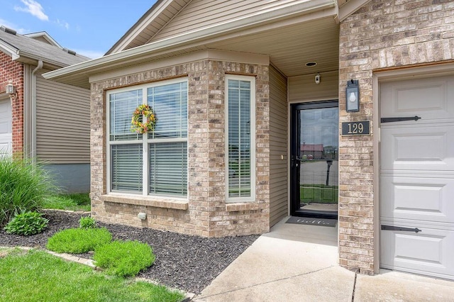 property entrance with brick siding and a garage