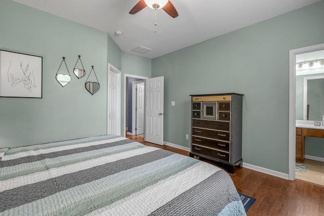 bedroom featuring wood finished floors, baseboards, ensuite bath, and ceiling fan