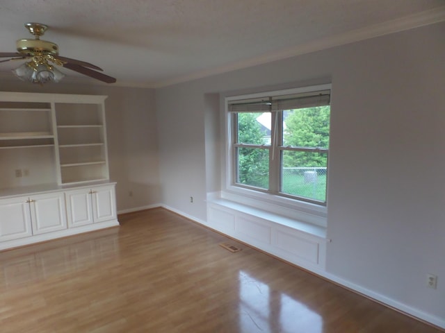 unfurnished room with light wood-style floors, ceiling fan, baseboards, and ornamental molding