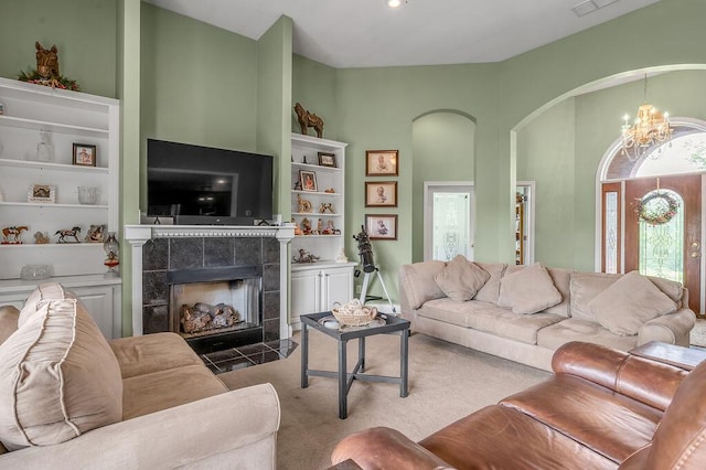 living room with a tile fireplace, arched walkways, a chandelier, carpet, and built in features