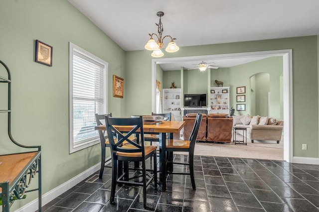 dining room featuring ceiling fan, arched walkways, baseboards, and a chandelier