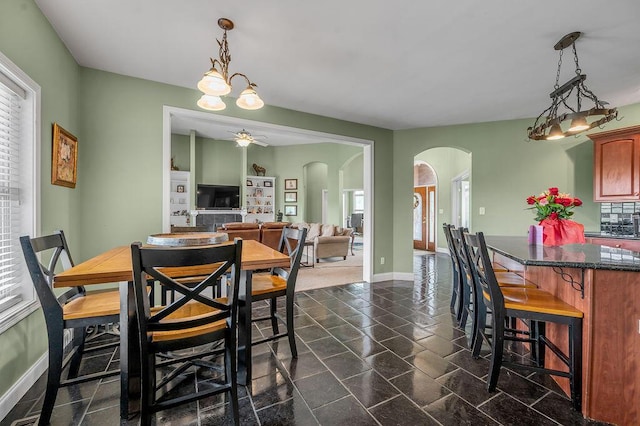 dining area with arched walkways, plenty of natural light, a ceiling fan, and baseboards