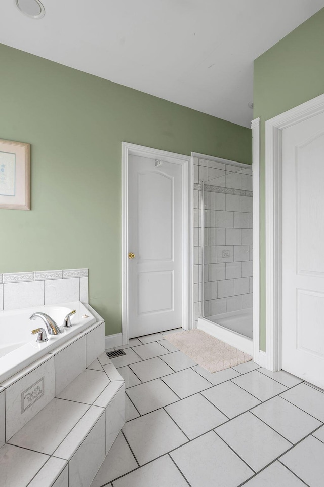 bathroom featuring a stall shower, a garden tub, tile patterned flooring, and baseboards