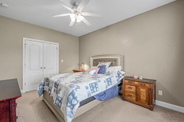 bedroom with light carpet, a closet, baseboards, and a ceiling fan