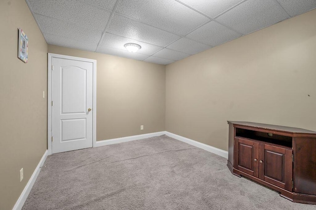 basement with a drop ceiling, carpet flooring, and baseboards