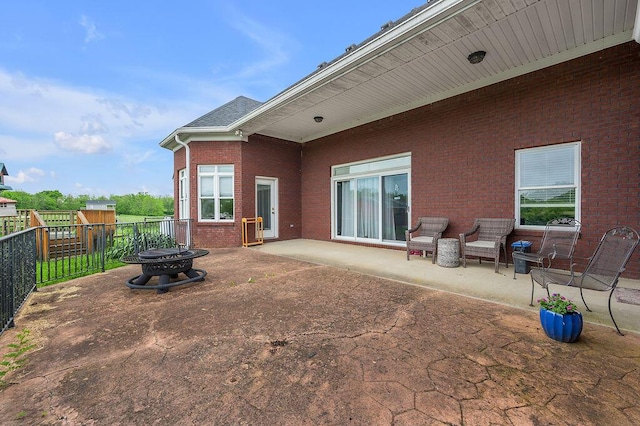 back of house featuring a fire pit, a patio, a fenced backyard, and brick siding