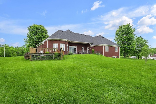 rear view of property with a lawn, brick siding, and a wooden deck