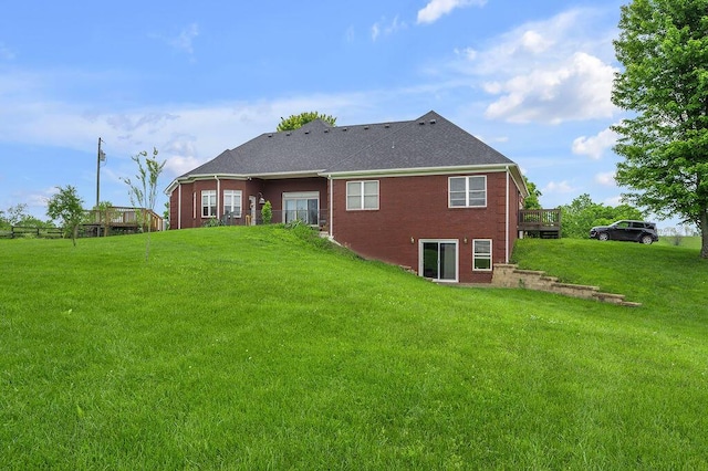 back of house featuring brick siding, a yard, and roof with shingles