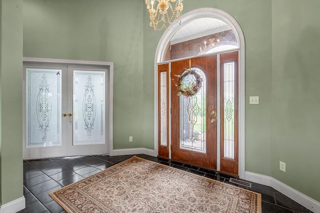 foyer entrance featuring a chandelier, baseboards, inlaid floor details, and french doors