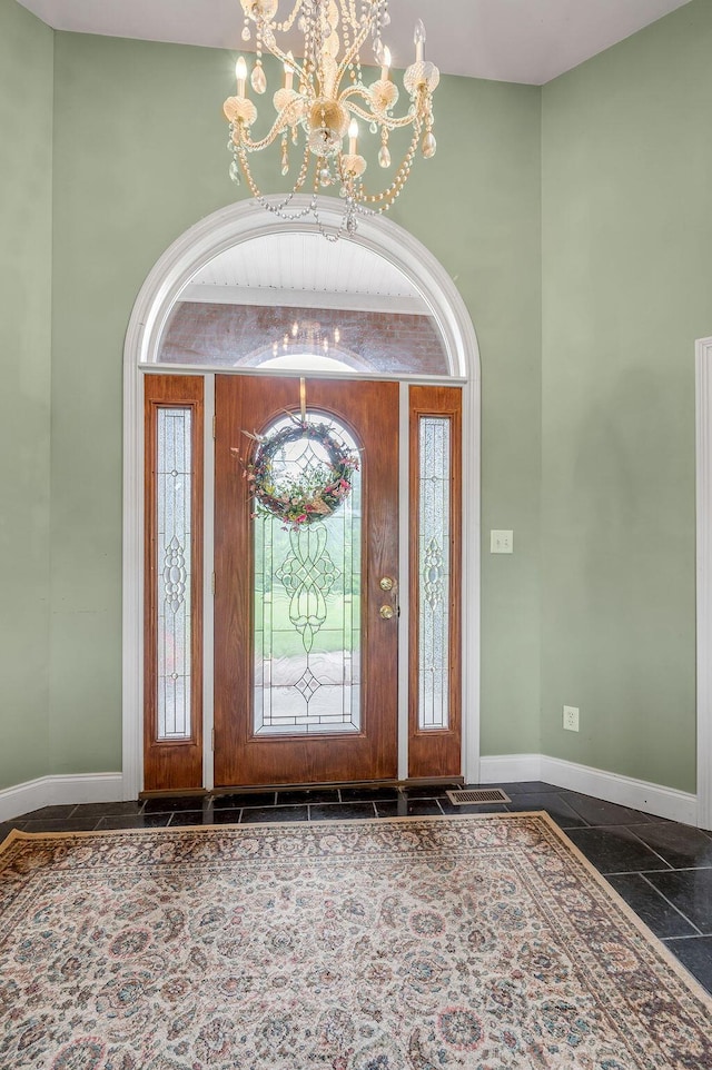 foyer featuring baseboards, a chandelier, and inlaid floor details