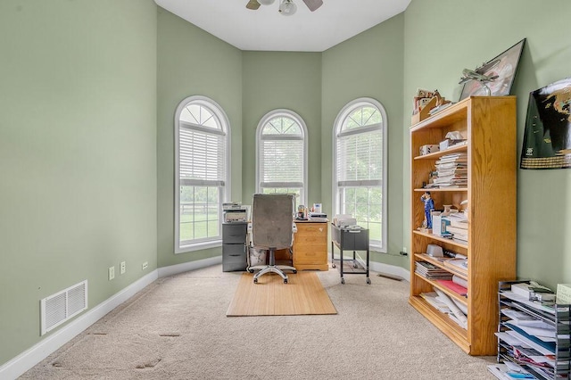 office featuring carpet floors, baseboards, ceiling fan, and a high ceiling
