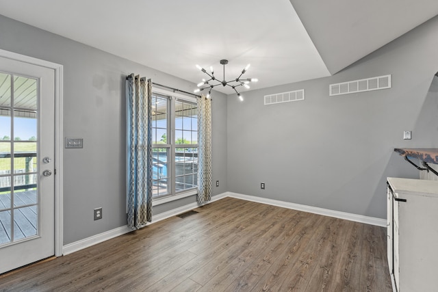 unfurnished dining area featuring a chandelier, wood finished floors, and baseboards