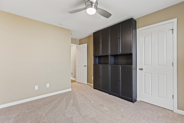 unfurnished bedroom featuring light colored carpet, baseboards, and a ceiling fan