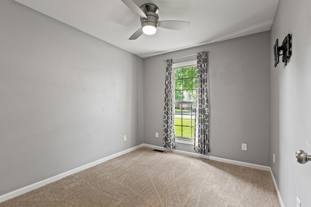 carpeted empty room featuring a ceiling fan and baseboards