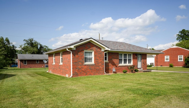 view of front of home featuring brick siding, a front yard, and roof with shingles