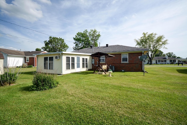 rear view of property featuring a yard, brick siding, and central AC