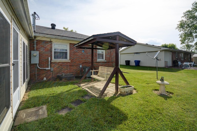 rear view of property with brick siding, a lawn, and a patio