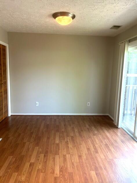 3440 Sutherland Dr, Lexington, KY 40517 - empty room with wood finished floors, a textured ceiling, healthy amount of natural light, and baseboards