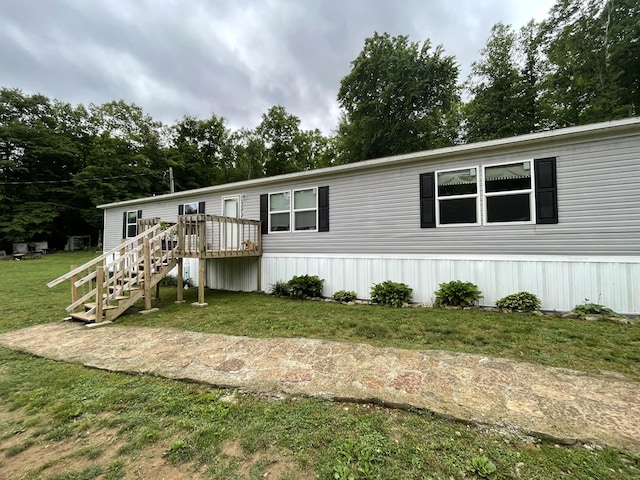 manufactured / mobile home with a deck, a front yard, and stairway