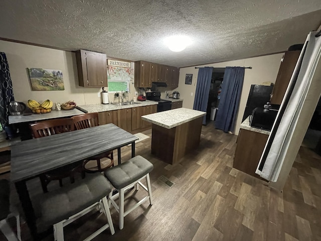 kitchen featuring light countertops, a center island, dark wood-style floors, black range with electric stovetop, and a textured ceiling