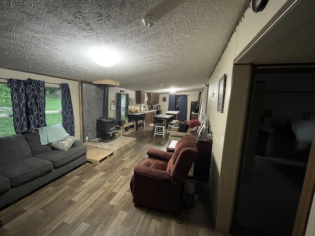 living room with a wood stove, wood finished floors, and a textured ceiling