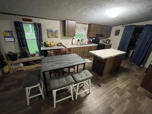 kitchen featuring black range with electric cooktop, light countertops, dark wood-style flooring, a textured ceiling, and a kitchen island