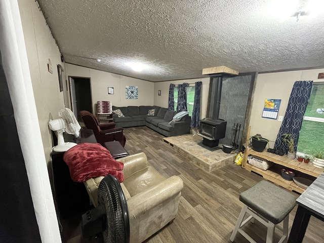 living room with wood finished floors, a textured ceiling, and a wood stove