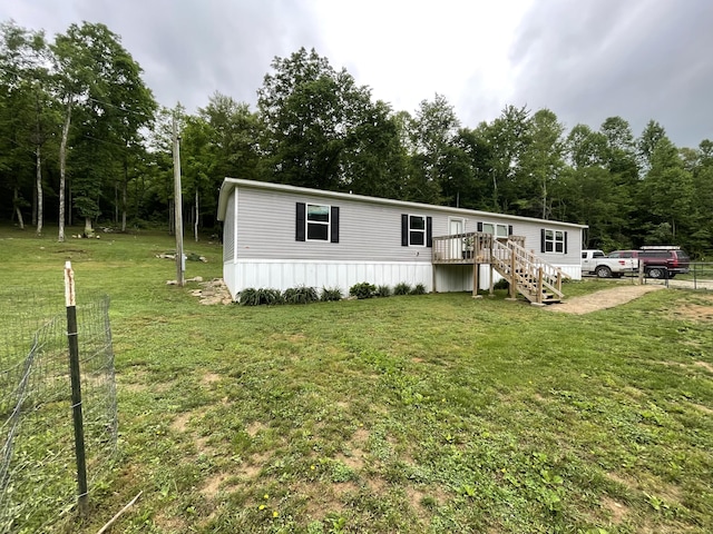 manufactured / mobile home with stairs, a deck, and a front lawn
