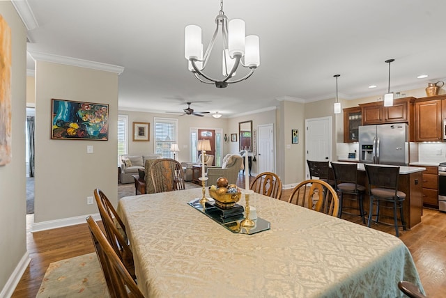 dining space featuring dark wood-style floors, baseboards, ceiling fan, crown molding, and a chandelier