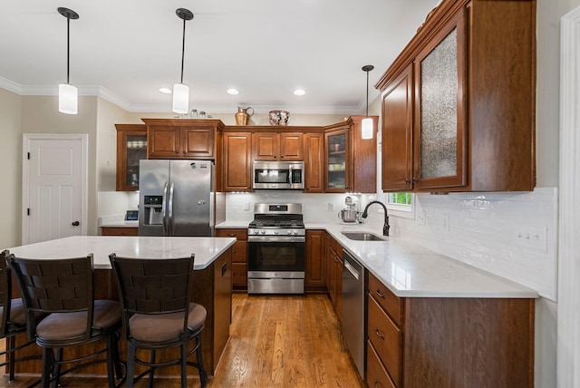 kitchen with stainless steel appliances, a sink, ornamental molding, backsplash, and a kitchen bar