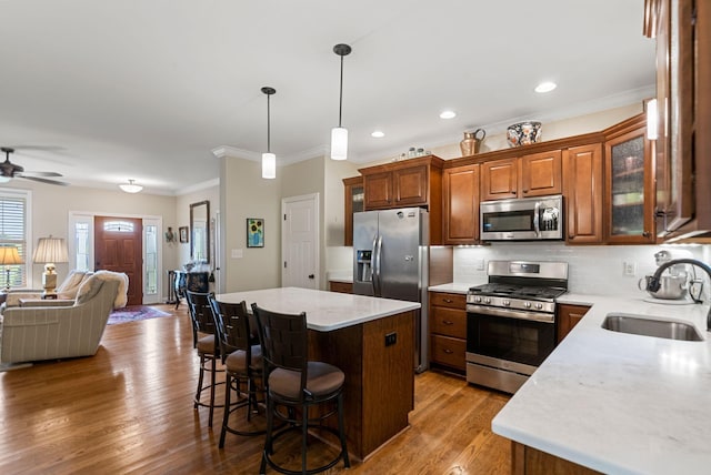 kitchen with appliances with stainless steel finishes, a sink, open floor plan, a kitchen breakfast bar, and a ceiling fan