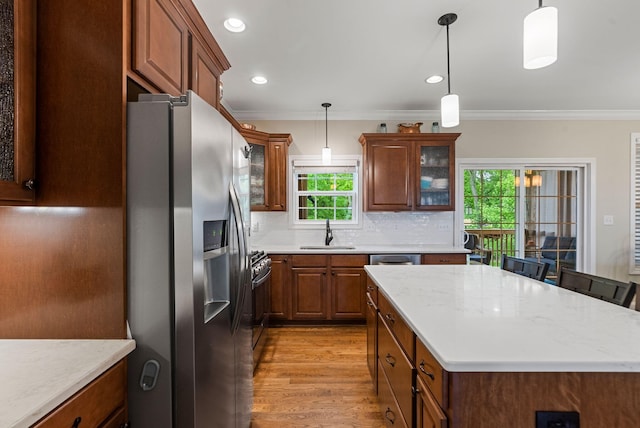 kitchen with stainless steel refrigerator with ice dispenser, a sink, a center island, gas range oven, and ornamental molding