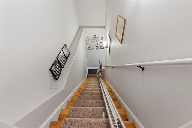 staircase featuring baseboards and wood finished floors