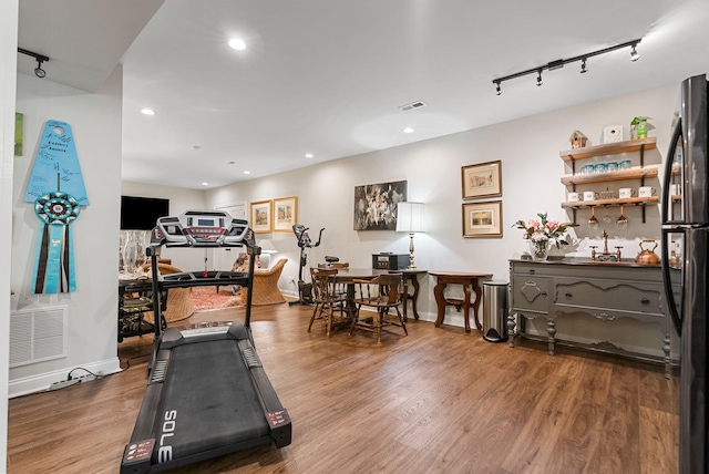 exercise area featuring rail lighting, wood finished floors, recessed lighting, and baseboards