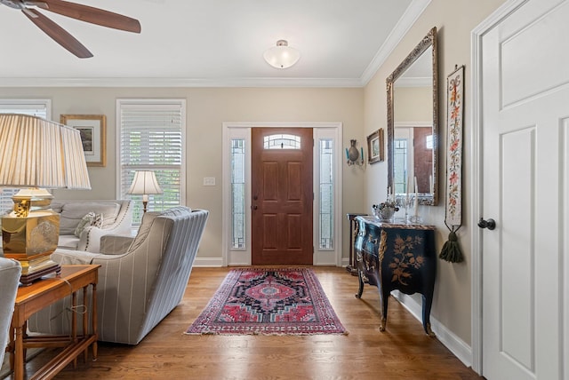 entryway featuring ornamental molding, wood finished floors, a ceiling fan, and baseboards