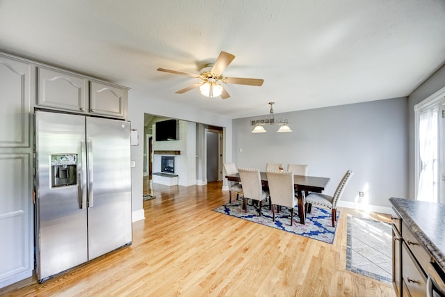 44 Gwinn Island Cir, Danville, KY 40422 - dining area with light wood-type flooring, baseboards, a fireplace with raised hearth, and ceiling fan