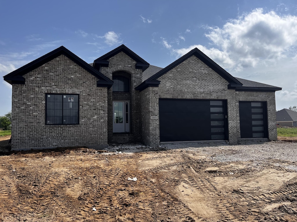 french country style house with brick siding, a garage, and driveway