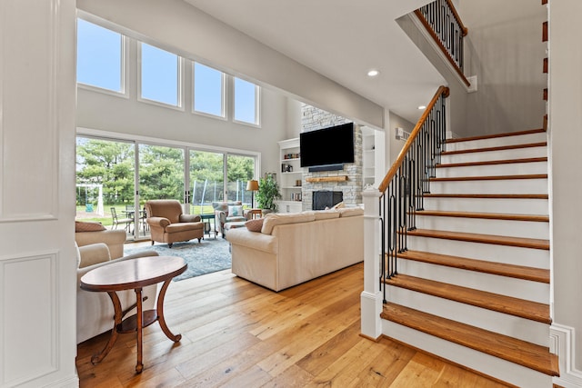502 W Brannon Rd, Nicholasville, KY 40356 - living room featuring light wood-type flooring, stairs, a stone fireplace, recessed lighting, and a high ceiling
